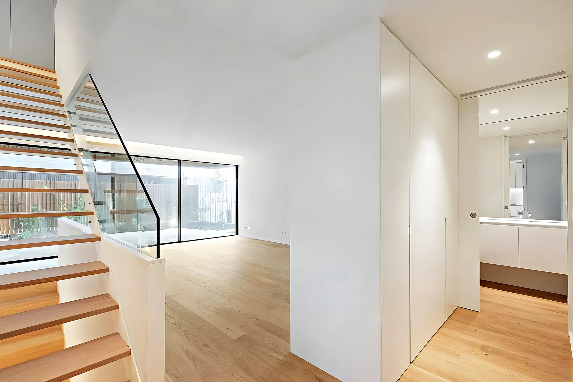 Salón con escalera de madera y barandilla de cristal — obra entregada en Fuengirola